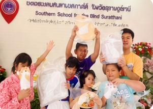 Children at the Southern School for the Blind holding up their gift bags